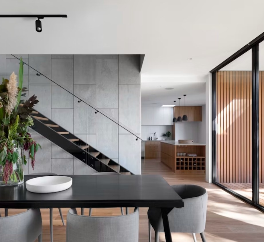 Open-plan living and dining space with a floating staircase, oak kitchen and full-height glazing